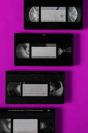 Lilac background with video cassettes. Four plastic video cassettes with a family video archive....