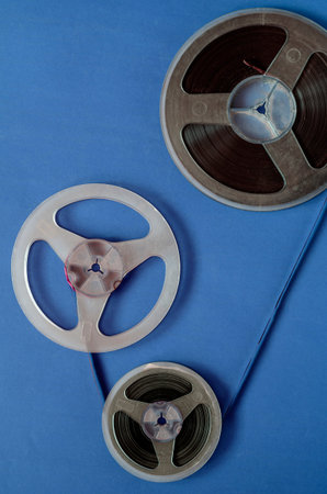 Three reels connected by audio tape. Composition of audio reels simulating the reproduction of an analogue music film. Old bobbins with dust and scratches.の写真素材
