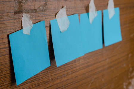 Four turquoise sheets for notes on a wooden billboard. Shabby shield with blank forms glued to it....