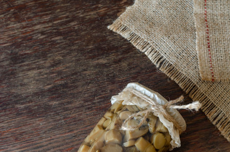 Glass jar with canned forest mushrooms on a wooden background. Canned food in a glass jar. Canning and storage of products in the cellar. Close-up.の写真素材