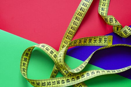 Measuring tape on a colorful background. Yellow tailor meter on a three-color background. Multitask background. Place for text. View from above.の写真素材