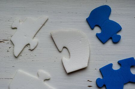 Unassembled puzzle pieces on white cracked paint. Blue and white puzzle pieces on an old wooden table. The concept of an old unsolved problem. Psychological trauma in childhood. Close-up.の写真素材