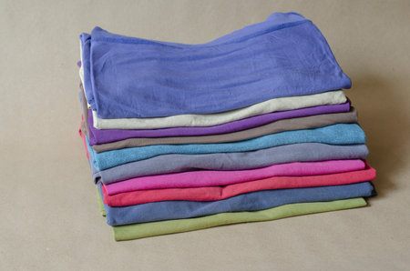 Ten t-shirts of different colors. Set of multi-colored t-shirts. A stack of trendy t-shirts closeup....