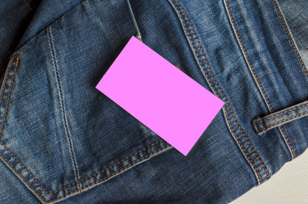 Pink business card over the back pocket of jeans. Closeup of the back of a jeans with a blank form....