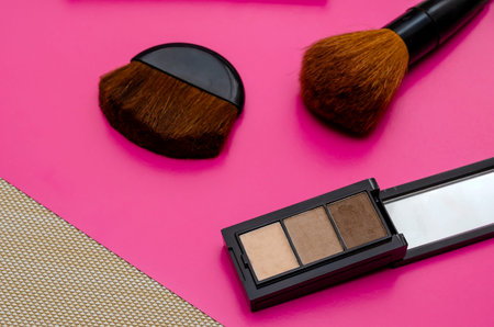 Creative harmonious background with decorative cosmetics items. Set of eye shadow and makeup brushes...
