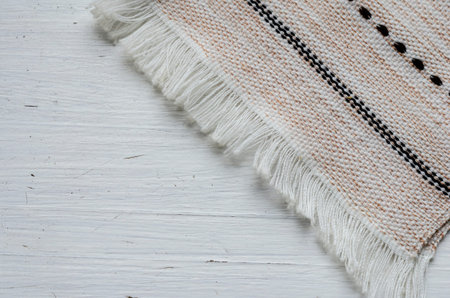 Linen towel with fringe on a white wooden background. Old wooden background with cracked paint....
