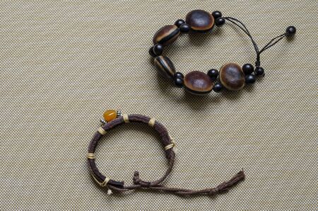 Handmade bracelets for women on a beige textured background. Brown bracelets made of leather and wood close-up. Free space for text. View from above.の写真素材