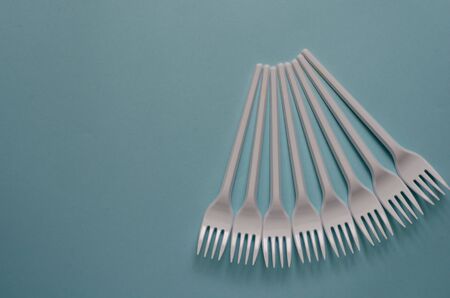 Abstract background with disposable cutlery. Geometric shape made of plastic forks on a light blue background. Group of White disposable forks. Serving, food industry. View from above. Selective focus.の写真素材