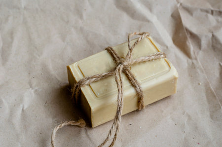A piece of laundry soap on a plain background. A single rectangular piece of new soap wrapped with...