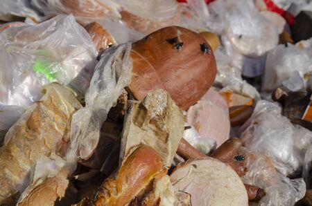 Spoiled sausages close-up. Various unsuitable foods in a trash can. Trash bin outdoors. Close-up. Selective focus.の写真素材