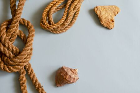 Background on the marine theme, spa, travel or beach vacation. Hemp rope, seashell and a heart-shaped stone on a light blue background. Calm colors. Place for text. View from above.の写真素材