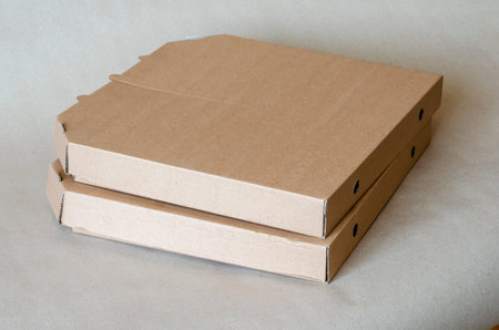 Cardboard boxes for pizza close-up. Two closed brown boxes in a stack. Food packaging and delivery....
