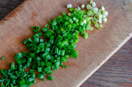 Chopped green onions on a cutting board. A bunch of fresh chopped chives. The process of preparing a...