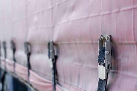 Fragment of Tarpaulin Truck. A line of metal fasteners with straps. Freight commercial transport, logistics. Focus in the foreground.の写真素材