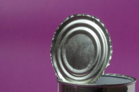 Open tin can lid close-up. Torn uneven edges of a metal cover on a purple background. Canned food. Place for textの写真素材