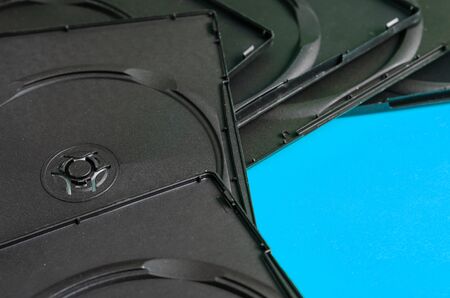 A collection of empty plastic boxes for DVD or blue ray discs. Black open boxes on a turquoise background. Abstract geometric background. Eye level shooting. Selective focus.の写真素材