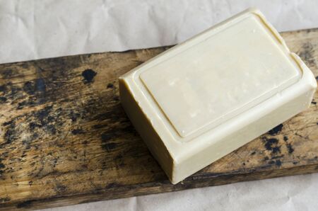 Briquette of laundry soap on an old wooden board. Demonstration of a single piece of new soap. Place for text. Natural hygiene products. Selective focus.の写真素材