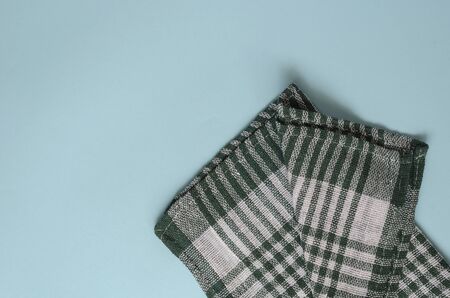 Light turquoise background with a green checkered towel. Kitchen linen towel folded casually. Minimalistic multitask background. View from above.の写真素材