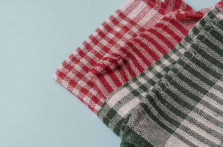 Two random kitchen towels on a light blue background close-up. Red with white and green with white towels. Place for text. Close-up.の写真素材