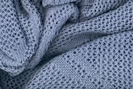 Texture of gray-blue knitted fabric. Repeating fabric pattern. Textile industry. Close-up.