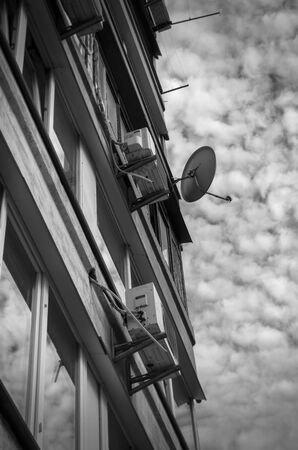 Real estate for rent background. The facade of multi-storey apartments with air conditioning on a background of cloudy sky. Living rooms with large windows. Monochromeの写真素材