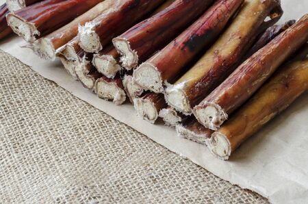Stack of bully pizzle for dogs close-up. Group of dental bully sticks on brown paper. Pet shop, pet supplies creative background.の写真素材