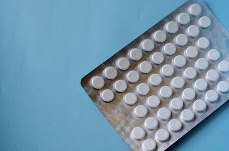 Creative background medical theme. Blister with a lot of pills on a turquoise background. Copy space. Eye level shooting.の写真素材