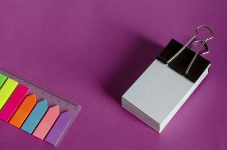 A set of colored bookmarks and a stack of blank business cards lies on a lilac surface. Centimeter ruler and clip. Lilac, coral, blue, orange, red, yellow, green, blue. Copy space.の写真素材