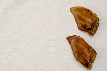 Dried pork ears for dogs. Natural chewing treats. Pet supplies for dental health. Copy space. View from above.の写真素材