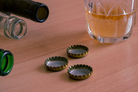 Alcoholism social problem, background. Beer glass with unfinished beer, three random empty bottles...