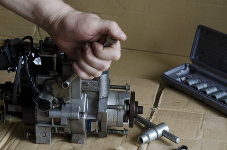 Repair of a diesel fuel pump of a high pressure. Car mechanic unscrews bolts with a wrench. Car service. Close-up. Selective focusの写真素材