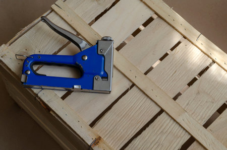 Blue industrial stapler and wooden box in the sunshine indoors. Production of environmentally...