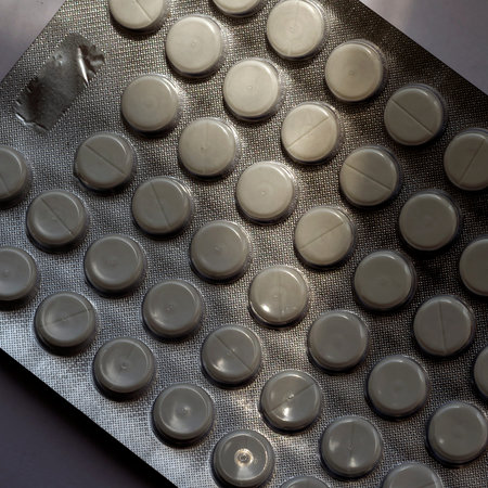 Blister of 50 tablets close-up. Round white pills in the sun. Medical topics. Health care.