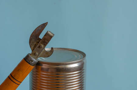 Closed can and can opener. Canned food and a special knife. Long-term storage products. Close-up. Copy space.の写真素材