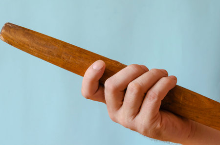 Hand holds a wooden rolling pin. The right hand of a person with a device for rolling out the dough....