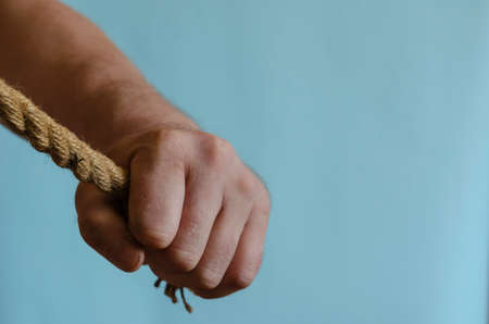 Hemp rope in a man's hand. The hand holds a thick natural cable. Adult male of European race. Interaction concept.の写真素材