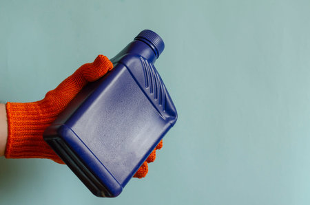 Full blue canister in a man's hand. Man's hand in a protective glove holds a plastic can of liquid....