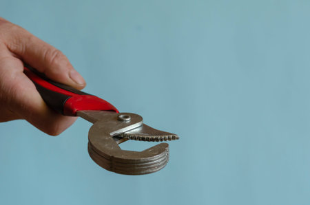 Universal wrench in a male hand. A man's hand shows a tool with a black and red handle. Middle-aged...