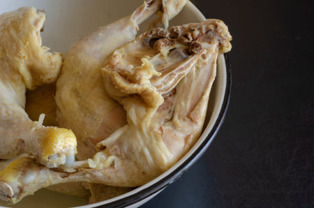 Boiled Chicken Leg Quarters. Serving of cooked chicken legs in a white metal bowl. Close-up....