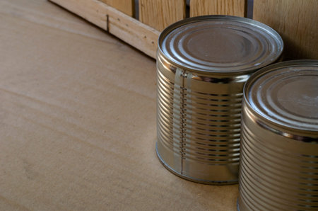 Two cans of canned food next to a wooden box. Close-up of canned food for long-term storage. Canned...