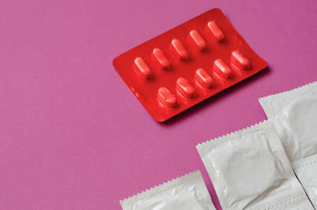 Bllister of medical pills and condoms on a pink background. Treatment and prevention of sexual dysfunction in men. Top view at an angle.の写真素材