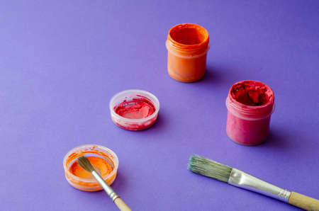 Drawing brushes and jars with gouache paint on a blue background. Various random brushes. Creativity, drawing. Close-up. Selective focus.の写真素材