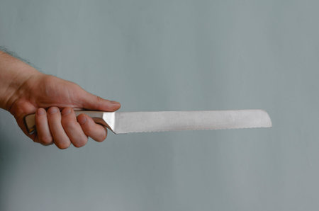 Adult man holds in his hand a knife for slicing bread with a metal handle. Special metal knife for...