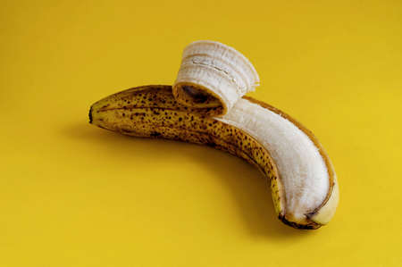 One overripe banana with brown spots on yellow background. Ingredients for banana bread, desserts and other dishes. Healthy eating. Selective focus.の写真素材