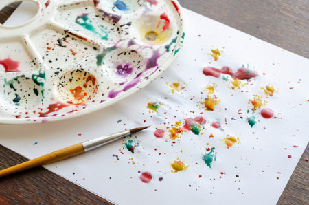 Close-up of a table splashed with watercolor paints and a sheet of paper. Teaching children to draw....
