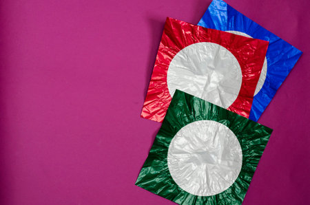 Three square pieces of colored foil on purple background. Pieces of foil are red, blue and green...