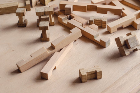 Details of the children's wooden constructor randomly on the wooden table. Close-up of a developing...