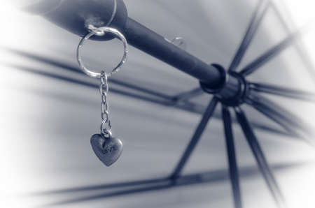 Heart-shaped keyring is attached to the handle of the umbrella. Close-up of love symbol. Shooting at eye level. Selective focus.の写真素材