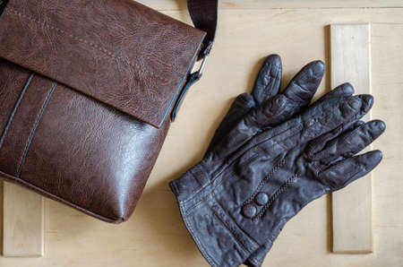 Leather gloves and bag on wooden background. Brown female leather gloves and small leather bag. Carelessly thrown clothing accessories.の写真素材