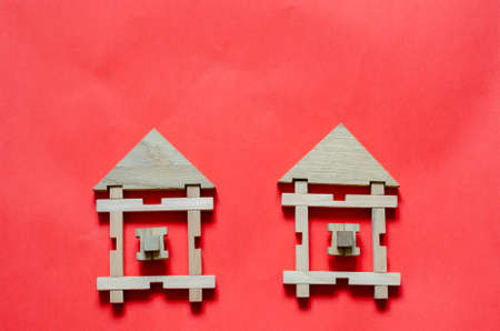 Two Wooden houses from a children's constructor on a coral background. Simple houses from wooden geometric details. Construction and rental of real estate concept. View from above. Copy space.の写真素材